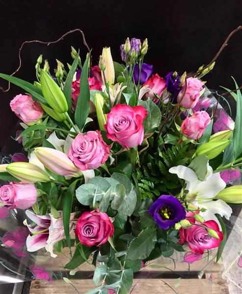 Margaret Raymond Florist Hand Tied Bouquet with bright pink roses and lilies, purple lisianthus, and twisted willow sticks